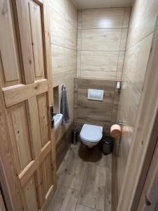 a small bathroom with a toilet and a wooden door at Chalupa pod lipenskou hrází in Loučovice