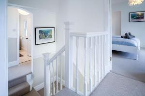 a white room with a staircase and a bed at Penlan - 3 Bedroom Cottage - Saundersfoot in Saundersfoot