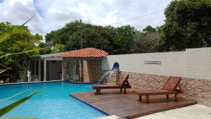 a swimming pool with two benches and a water fountain at Chácara da Bel in Pitimbu
