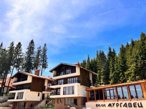 un gran edificio de apartamentos con árboles en el fondo en Boutique Villas Murgavets Pamporovo, en Pamporovo