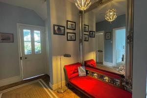 a living room with a red couch and a mirror at Luxury large coastal retreat near the sea in Deal