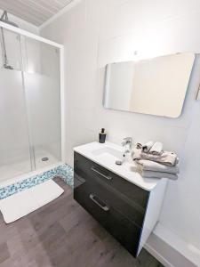 La salle de bains blanche est pourvue d'un lavabo et d'une douche. dans l'établissement Appartement Le Fort Vue montagne, à Villefranche-de-Conflent
