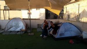 two people are standing next to two tents at Jerusalem Hostel in Jerusalem