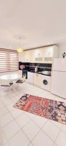 uma cozinha com armários brancos, uma mesa e um tapete em Best Home City 1 em Alanya