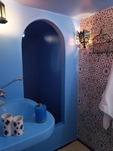 een badkamer met een blauw bad en een wastafel bij Appartement dans la médina in Asilah
