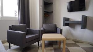 two chairs and a table in a room with a tv at riad casa bahia asilah in Asilah