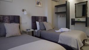 two beds in a hotel room with a mirror at riad casa bahia asilah in Asilah