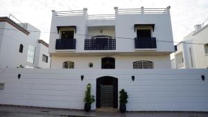 a white house with two plants in front of it at riad casa bahia asilah in Asilah