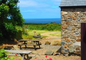 a picnic table and a stone building with the ocean in the background at Shicley in Trevine
