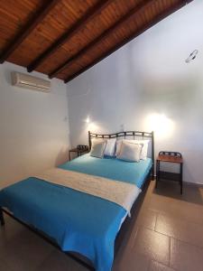 Schlafzimmer mit blauem Bett und Holzdecke in der Unterkunft Pension Anna in Patitiri