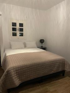uma cama num quarto branco com uma janela em Alesta em Aggelika