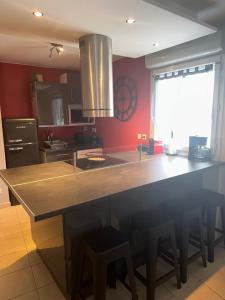 a kitchen with a large island in a kitchen with red walls at Superbe appartement tout équipé avec parking. in Marseille