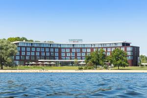 a large red building next to a body of water at Courtyard by Marriott Wolfsburg in Wolfsburg