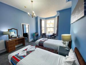 a blue room with two beds and a mirror at The Broadway Hotel in Llandudno