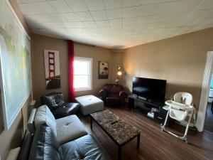 a living room with a couch and a tv at Auberge Lac-Saint-Jean in Roberval