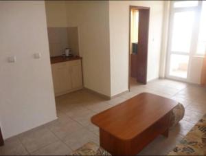 a living room with a wooden table and a kitchen at Къща за гости Бор in Pomorie