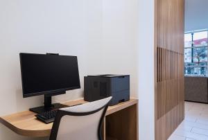 a computer monitor sitting on a desk with a chair at Element Dallas Las Colinas in Irving