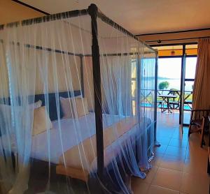 a bedroom with a canopy bed and a balcony at Kaazi Beach Resort in Kampala