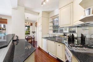 a kitchen with white cabinets and black counter tops at Double Bay Harbour-front apartment with stunning views in Sydney