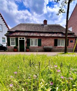 una casa de ladrillo rojo con un campo de hierba delante de ella en Het Kostershuisje, en Nuenen