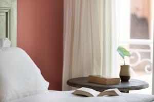 ein Bett mit einem Buch auf einem Tisch neben einem Fenster in der Unterkunft Tinos Resort in Tinos