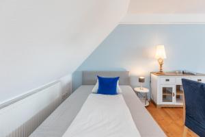 um quarto com uma cama com uma almofada azul em Kuestenwind em Husum