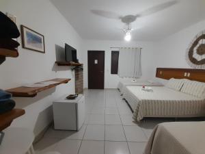 a white room with two beds and a tv at Pousada Galeão Santa Anna in Barra Grande