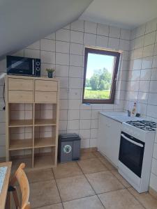 een kleine keuken met een fornuis en een raam bij Ogrodowe Noclegi 