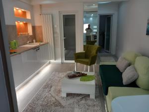 a living room with a couch and a chair and a kitchen at Apartman 101 in Sarajevo