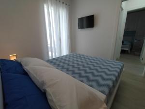 Bett in einem Zimmer mit einem TV an der Wand in der Unterkunft APARTMENT VELA SUITE in Alba Adriatica
