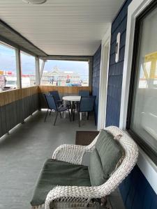 a balcony with a couch and a table and chairs at Nautical Beach Apartments in Hampton