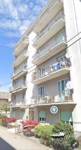 un edificio de apartamentos alto y blanco con balcones y plantas en Train Station Welcome A&A, en Santhià