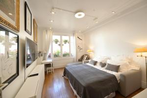 Habitación blanca con cama y TV en Villa d'art - Claire, en París