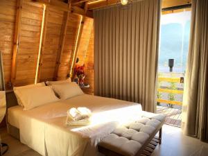 Un dormitorio con una gran cama blanca y una ventana en Cabana Relax - Picada Café, en Picada Café