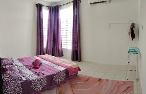 1 dormitorio con 1 cama con cortinas moradas y ventana en FS Homestay Cherating en Kuantan