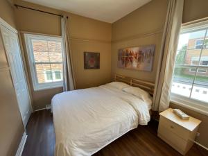 a bedroom with a white bed and two windows at Auberge Lac-Saint-Jean in Roberval