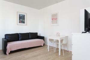 ein Wohnzimmer mit einem schwarzen Sofa und einem Tisch in der Unterkunft LG fond de cour F1 in Drancy