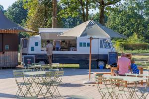 a food truck with people sitting at tables and an umbrella at Huttopia De Meinweg in Herkenbosch