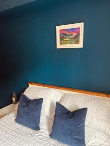 a bed with blue walls and two blue pillows at Waverley Court in Fort William