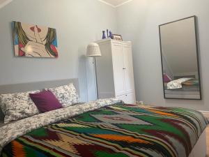 a bedroom with a bed with a colorful blanket and a mirror at Apartamet Gabriel in Tykocin