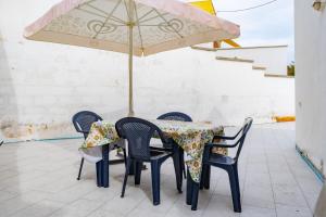 un tavolo con quattro sedie e un ombrellone di Casa al mare Le Campanelle a Marina di Pescoluse