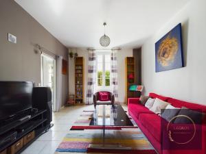 uma sala de estar com um sofá vermelho e uma televisão em Maison Mascle 5 personnes em Châteaurenard