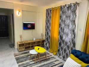 a living room with yellow curtains and a yellow table at Ruby Modern Homes-1br-Nyeri, King'ong'o-Marriott in Nyeri
