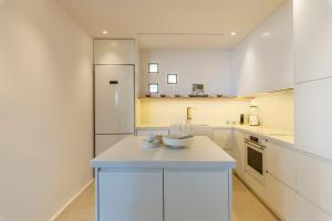 a kitchen with white cabinets and a white refrigerator at Villa Lilium II in Psarou