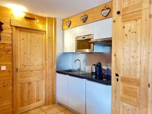 a kitchen with white cabinets and a sink at Appartement de charme au pied des pistes, centre des Gets, balcon et terrasse, 2 chambres, Wi-Fi gratuit - FR-1-623-268 in Les Gets