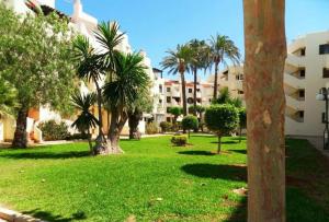 un parque con palmeras y un edificio en Acogedor apartamento en la Playa. Urbanización La Felicidad. Las Marinas en Dénia