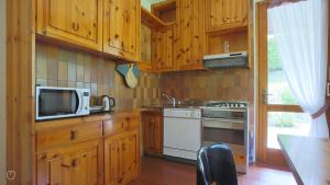 eine Küche mit Holzschränken, Mikrowelle und Herd in der Unterkunft Italianway - San Rocco 73 in San Fedele Intelvi