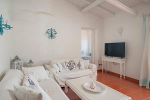 een woonkamer met witte meubels en een flatscreen-tv bij Casa Azzurra con Terrazza Vista Mare by Wonderful Italy in Golfo Aranci