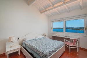 een slaapkamer met een bed, een bureau en een raam bij Casa Azzurra con Terrazza Vista Mare by Wonderful Italy in Golfo Aranci