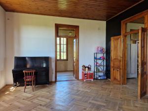een woonkamer met een piano en een houten vloer bij Villa Natanebi 